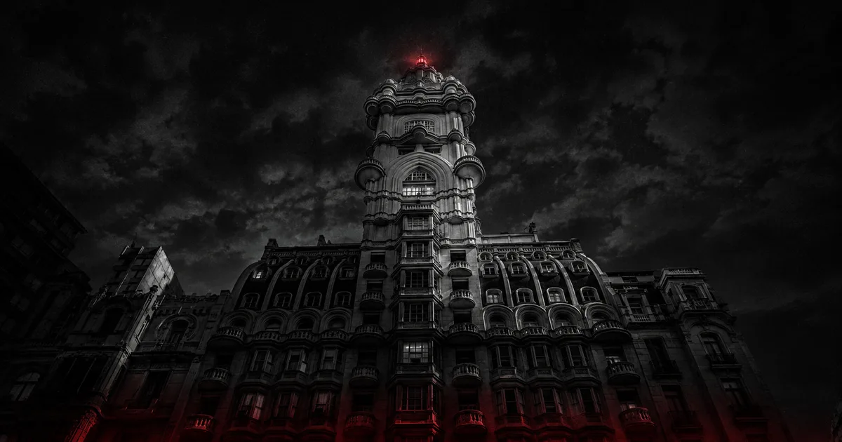 La imponente silueta del Palacio Barolo recortada contra el cielo nocturno de Buenos Aires, con su faro encendido en lo alto de la cúpula y un tenue resplandor rojo en su base